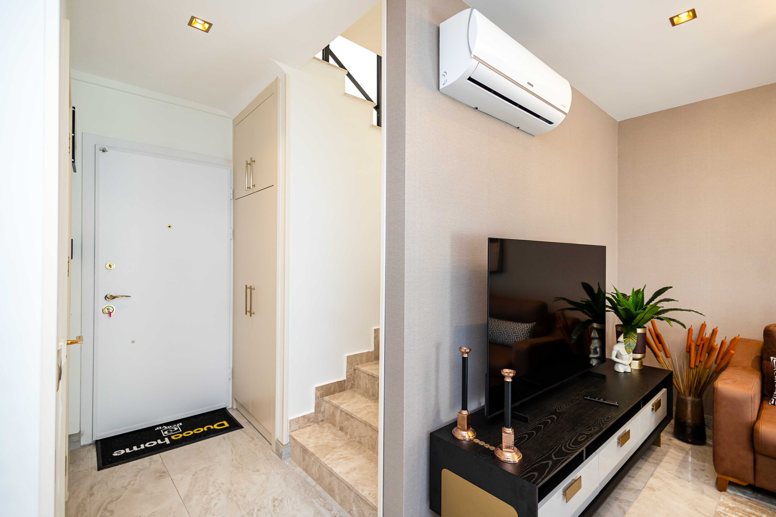 Living room with a brown corner sofa, television and marble staircase