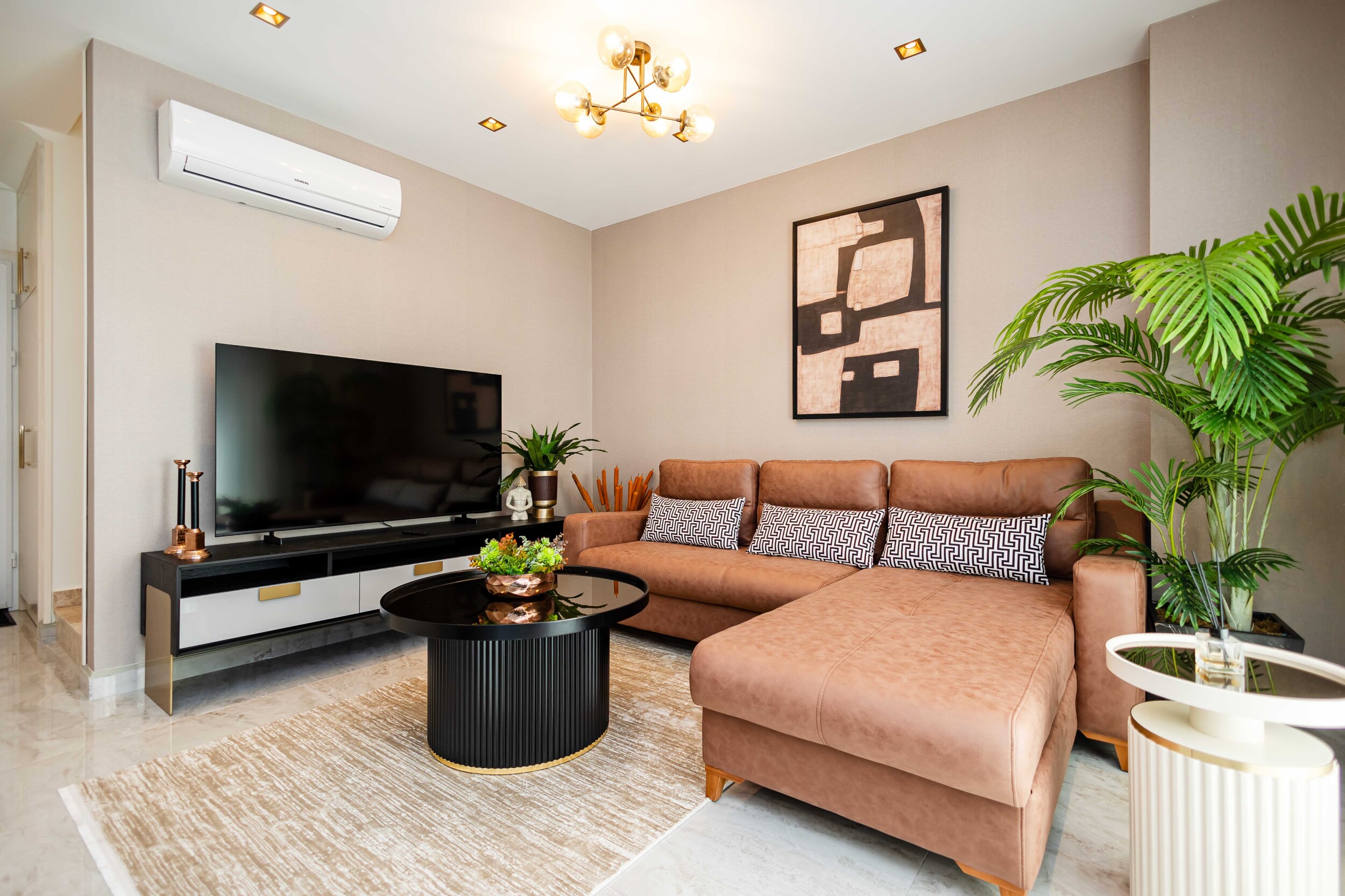 Living room with a corner sofa, television and houseplant in a penthouse for sale