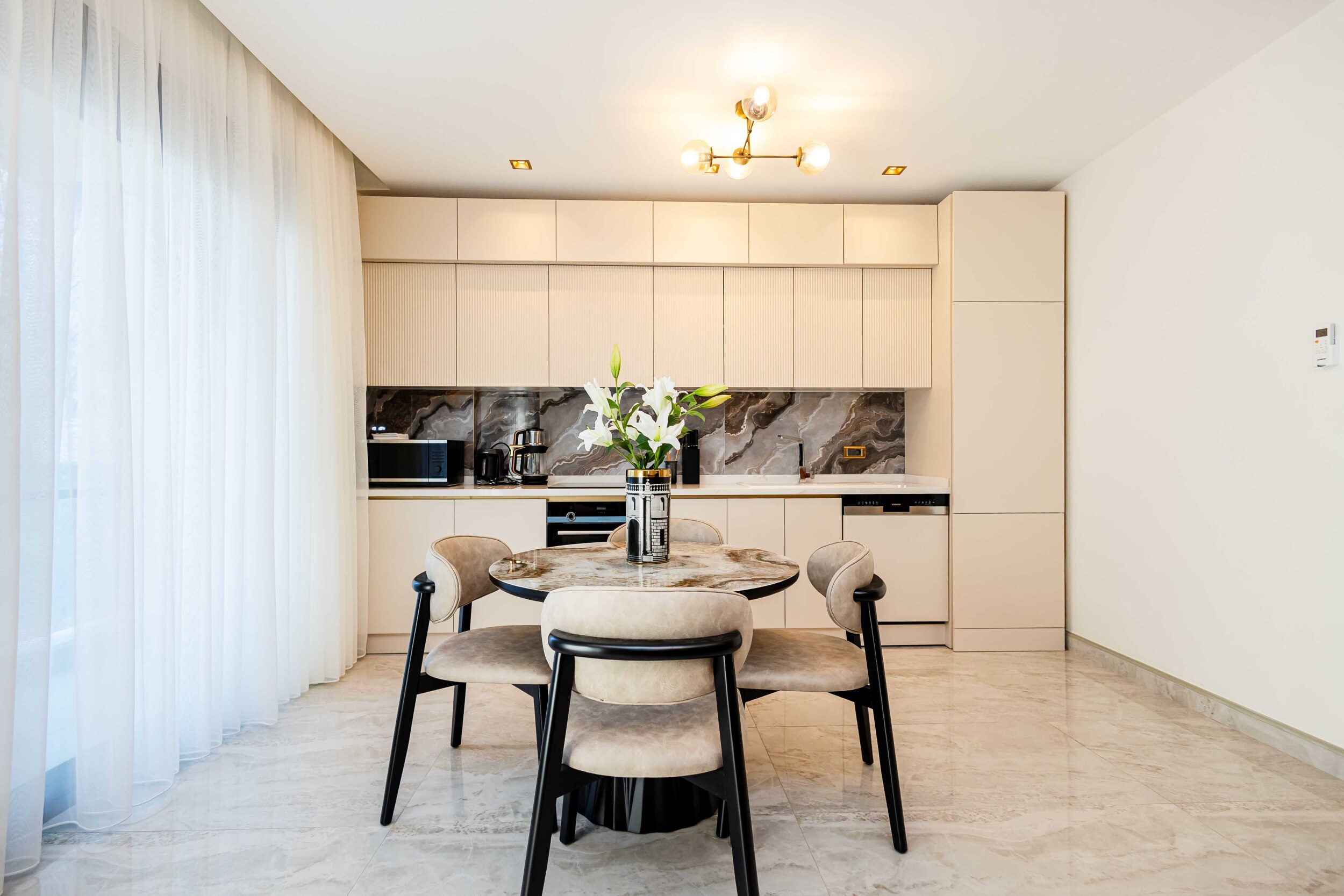 Kitchen with full-height cupboards and built-in oven beside a panoramic window in a penthouse by the sea