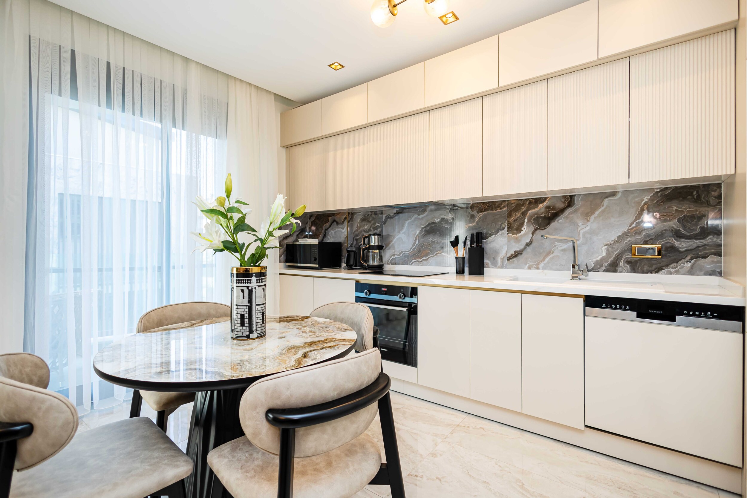 Kitchen-living room with beige cabinetry and marble countertops in a top-floor apartment