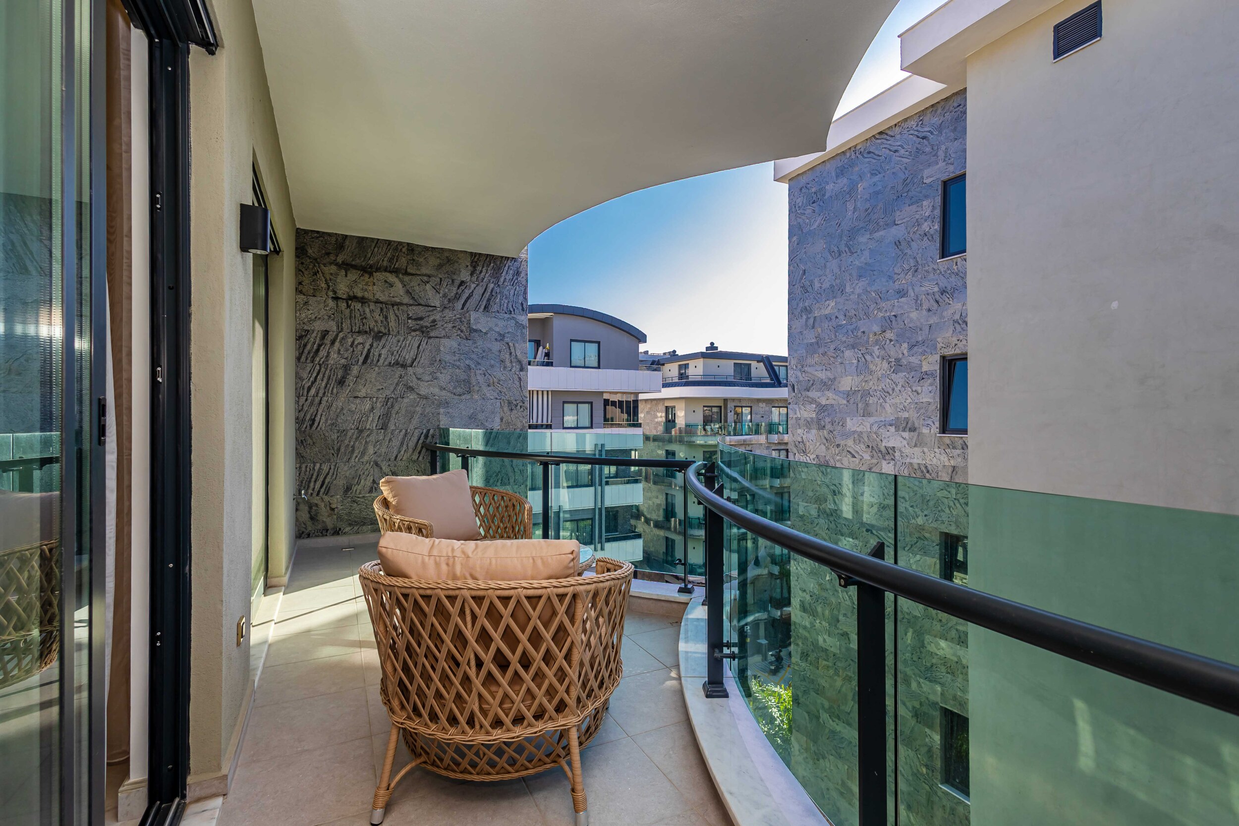 Curved balcony with wicker chairs and city views in a residence for sale in Turkey