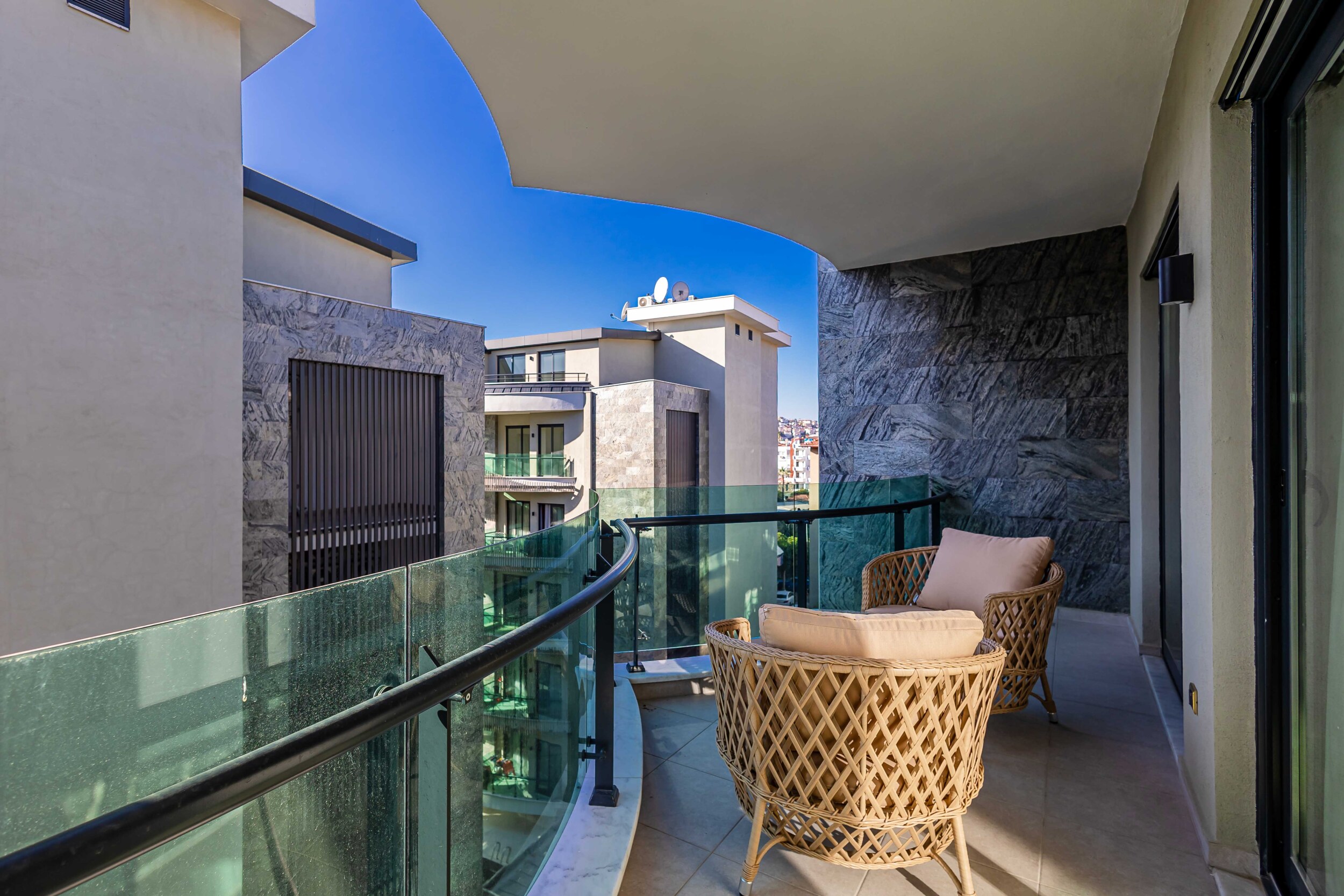 Curved balcony with glass railing and city views from a penthouse by the sea for sale