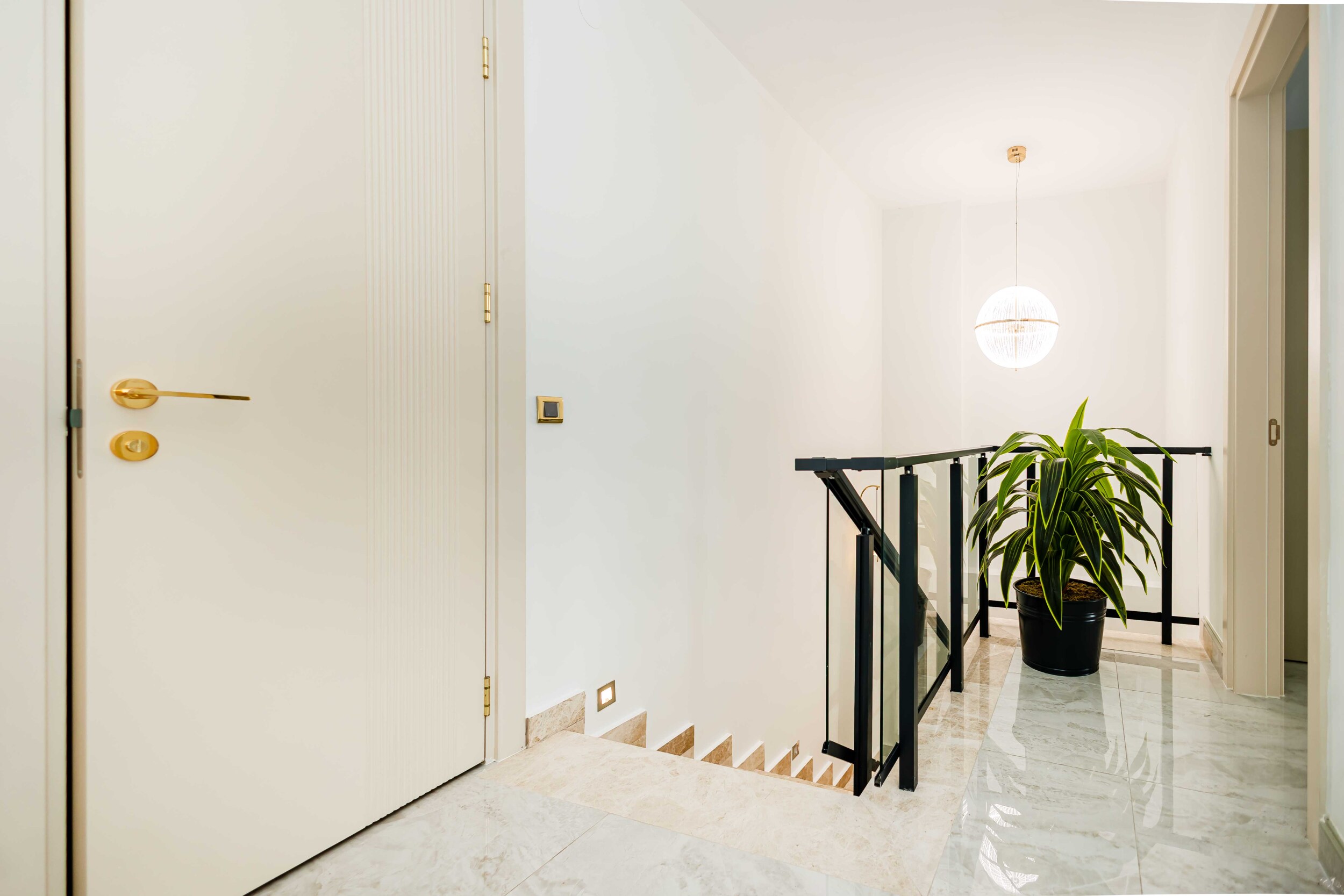 Hall with marble flooring, white doors and a potted plant by the sea