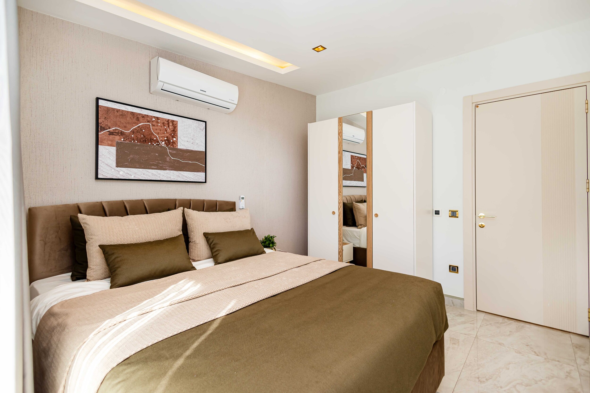 Bedroom with mirrored wardrobe and upholstered headboard in a top-floor apartment by the sea