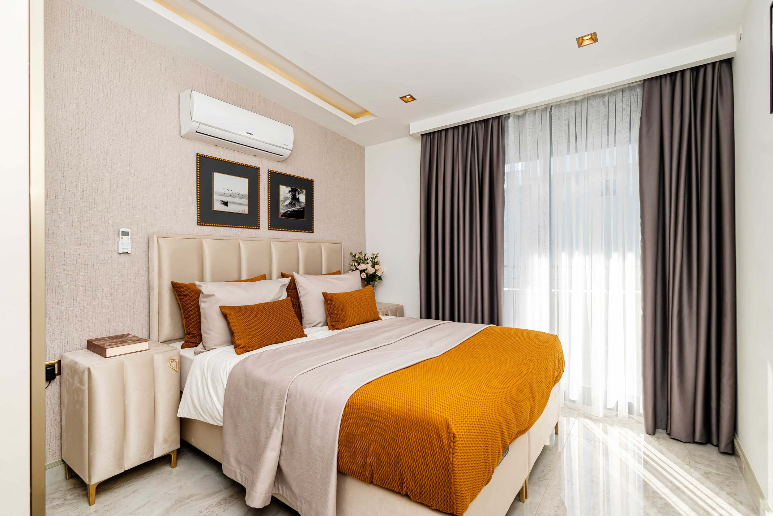 Bedroom with orange bedspread and vertical upholstered headboard in a penthouse