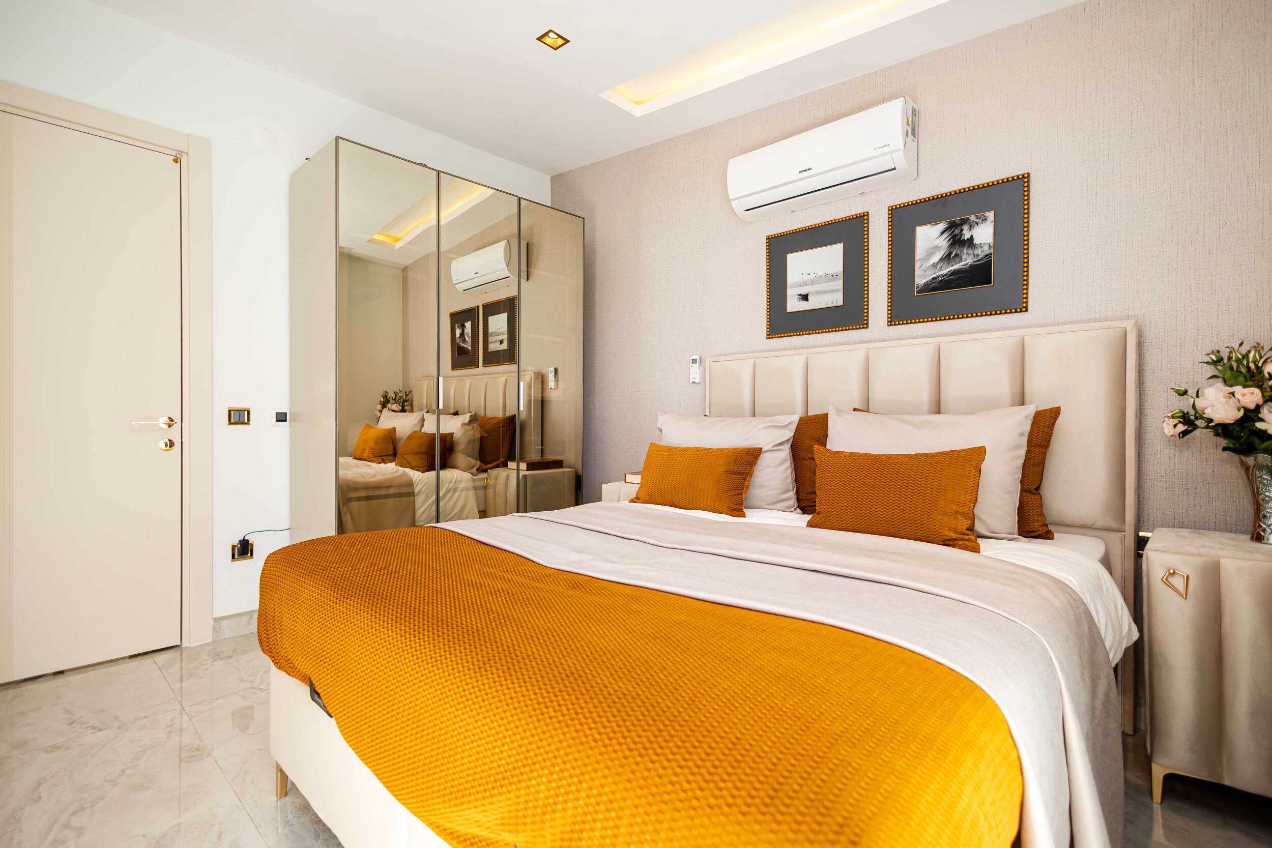 Bedroom with orange bedspread and mirrored wardrobe by the sea