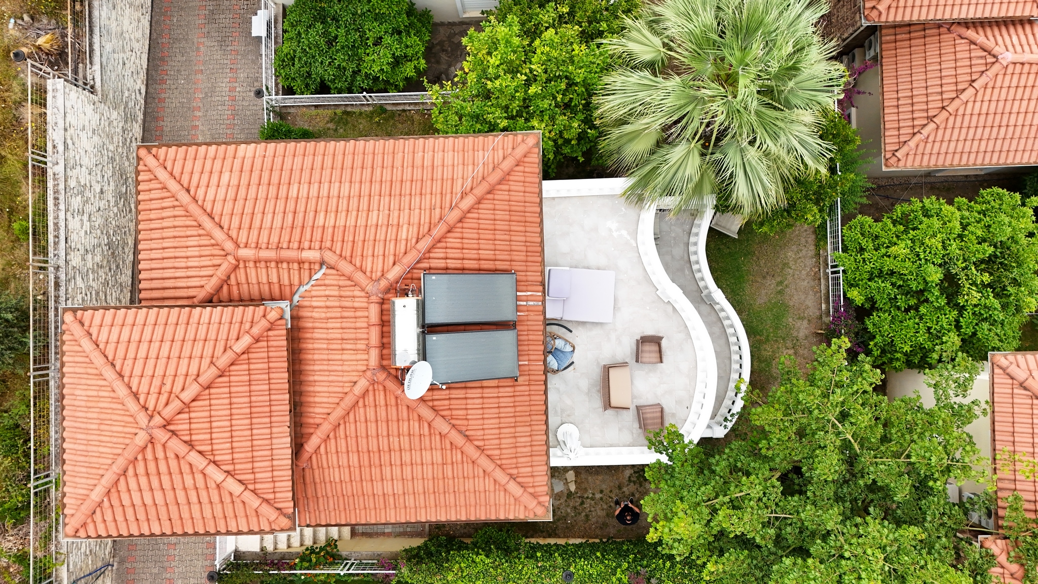 Top view of a tiled villa roof with solar panels, loungers and garden paths in Alanya where it is for sale