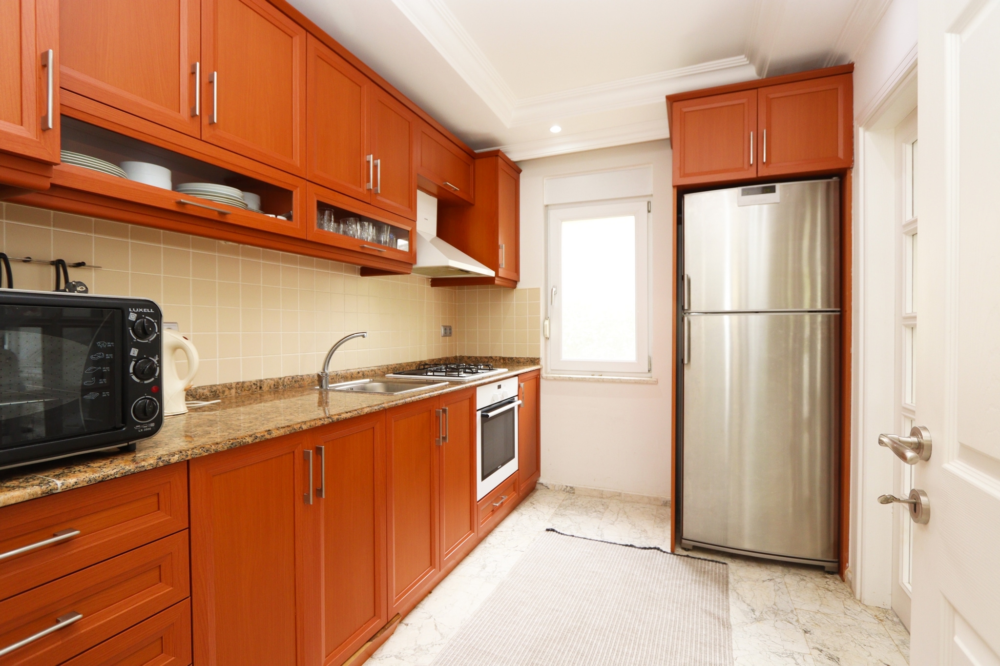 Kitchen with wooden cabinets, granite worktops and built-in appliances in a villa in Alanya