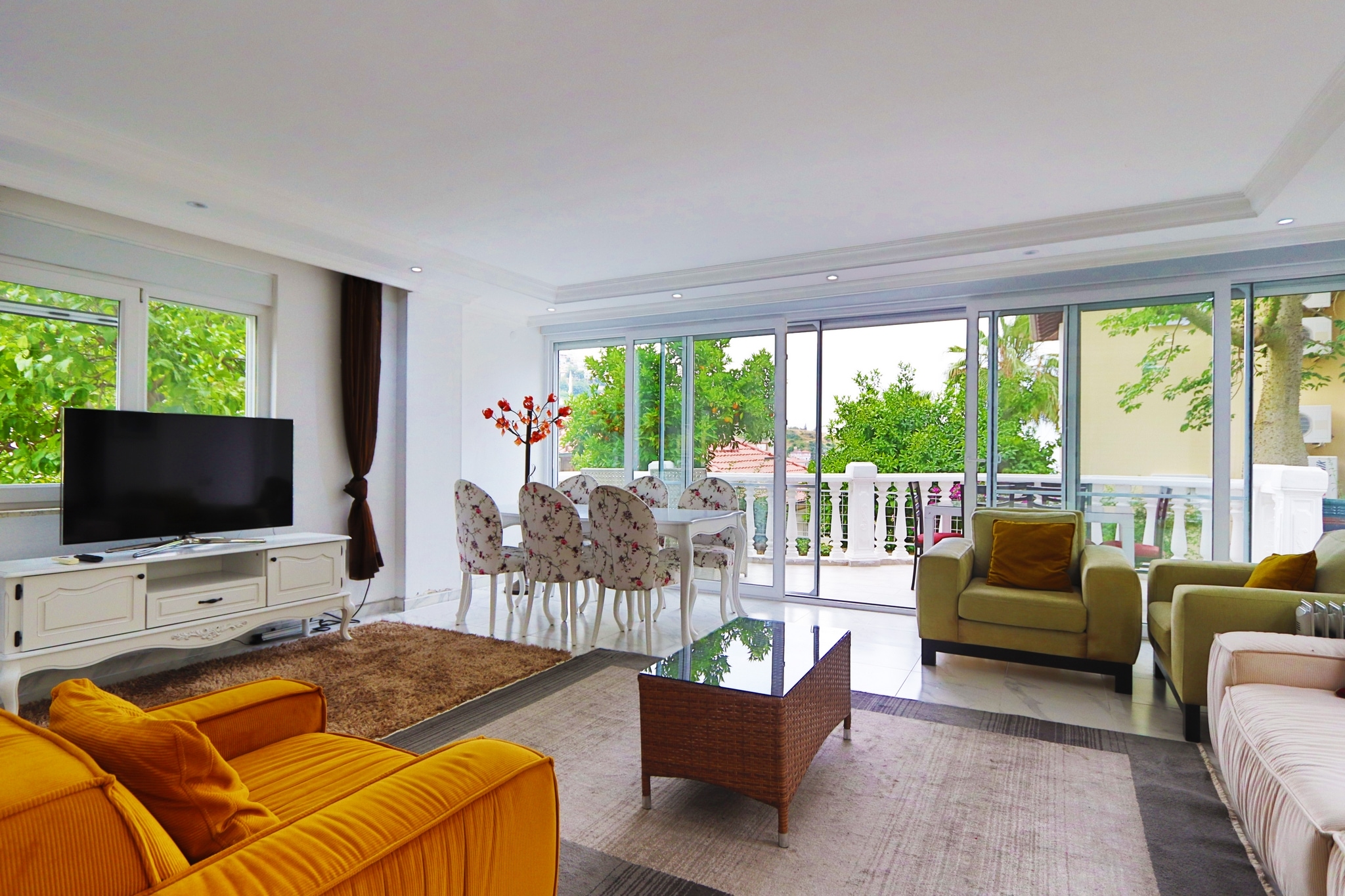 Kitchen-living room with an orange sofa, panoramic glazing and terrace access in a villa