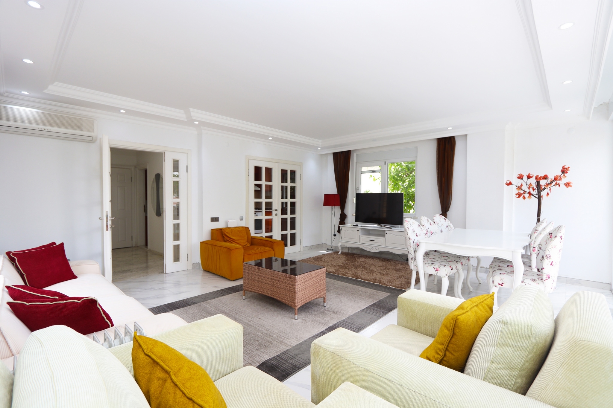 Kitchen-living room with a white sofa, colorful armchairs and glass doors in Alanya, Turkey