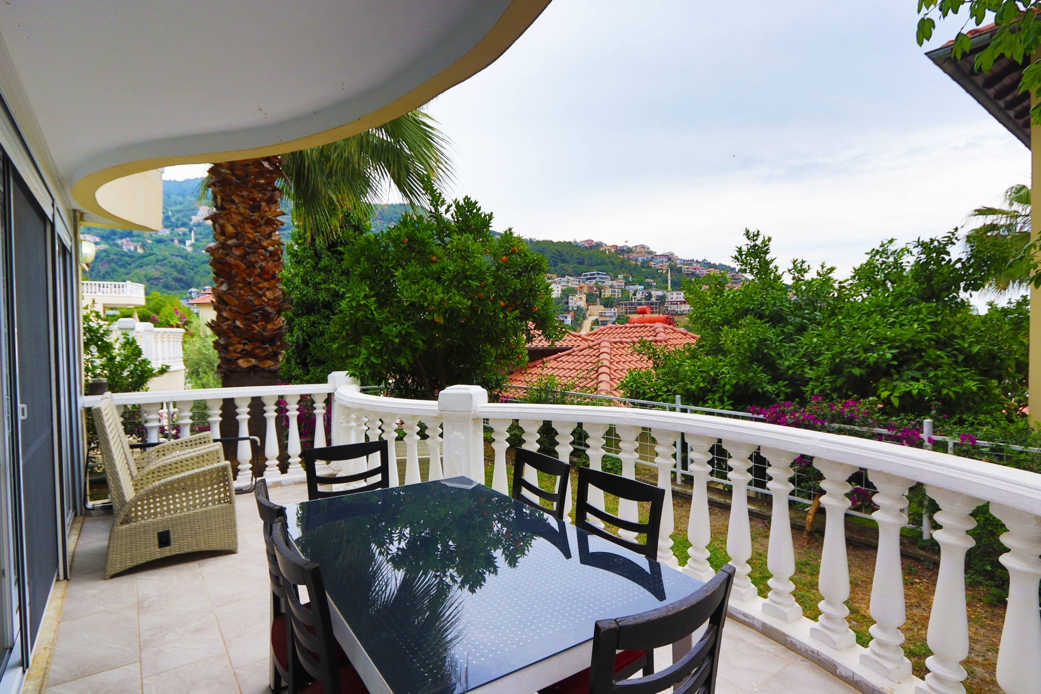 Terrace with a round glass table, four chairs and a white balustrade in Turkey