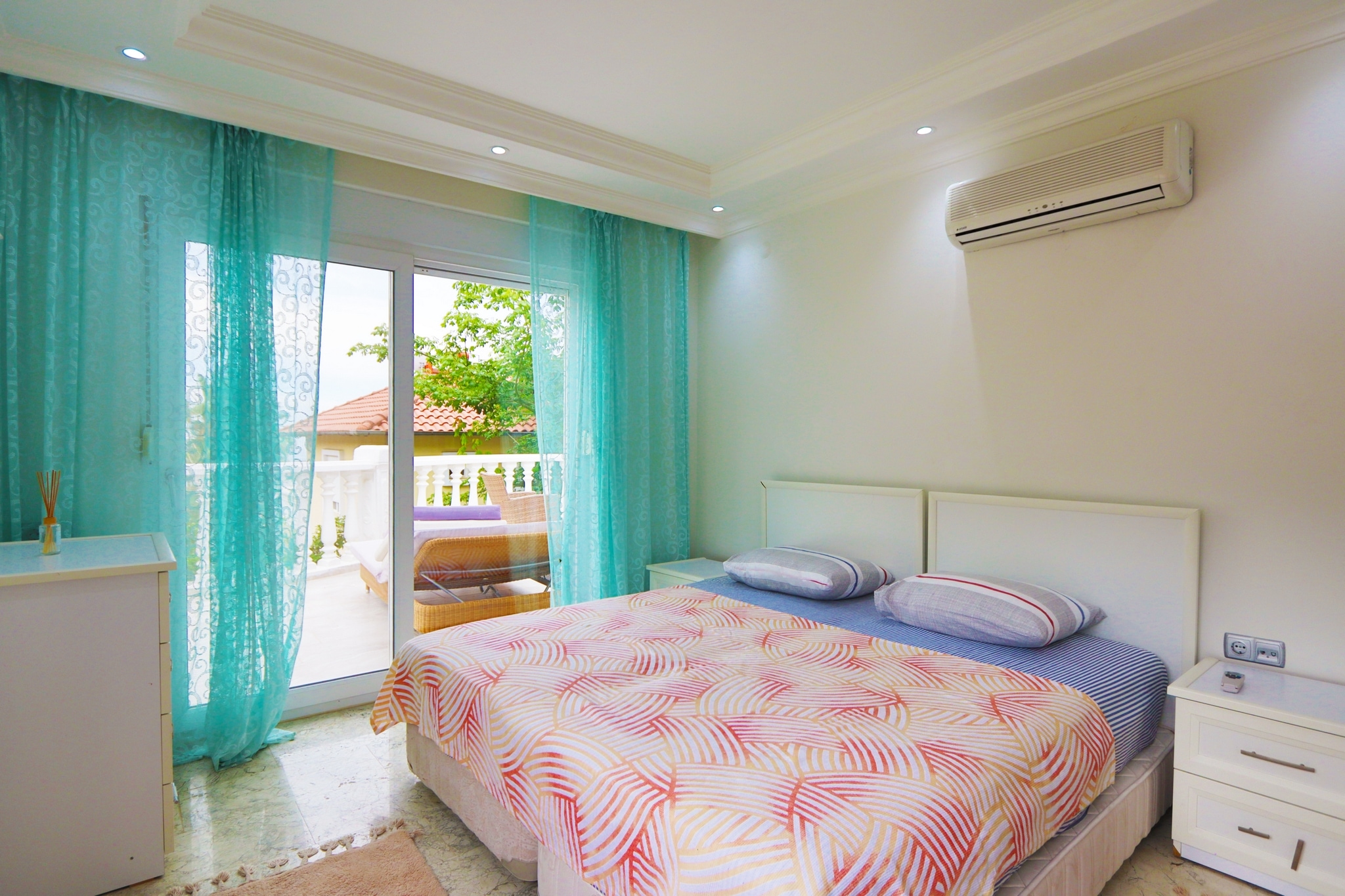 Bedroom with a double bed, turquoise curtains and a panoramic balcony door in a villa in Alanya
