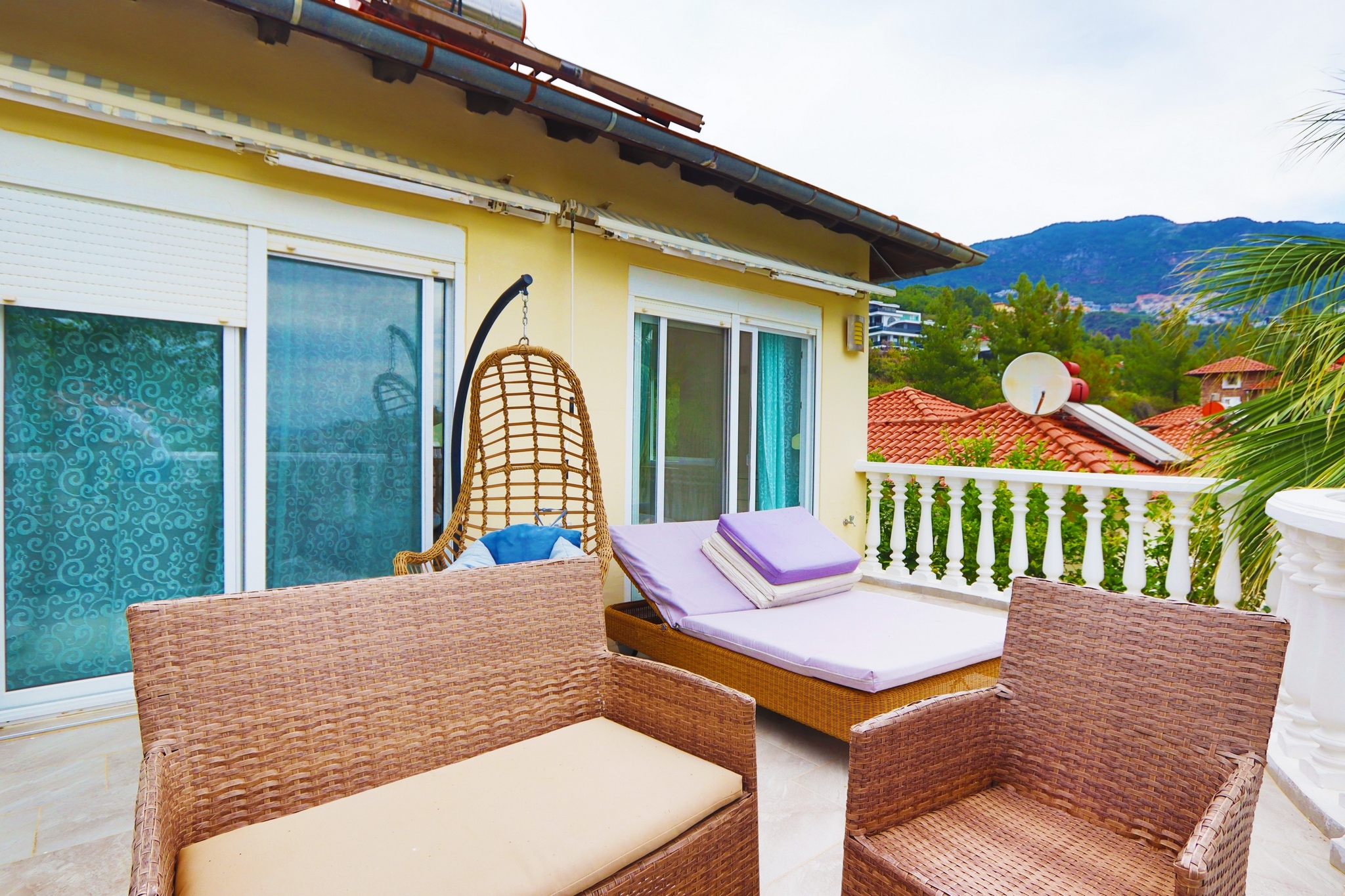 Balcony with wicker seating, sliding glass doors and a mountain view at a villa for sale