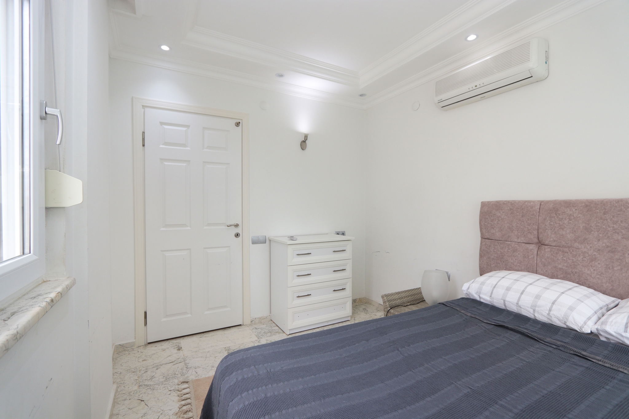 Bedroom with a double bed, textile headboard and white chest of drawers in a house