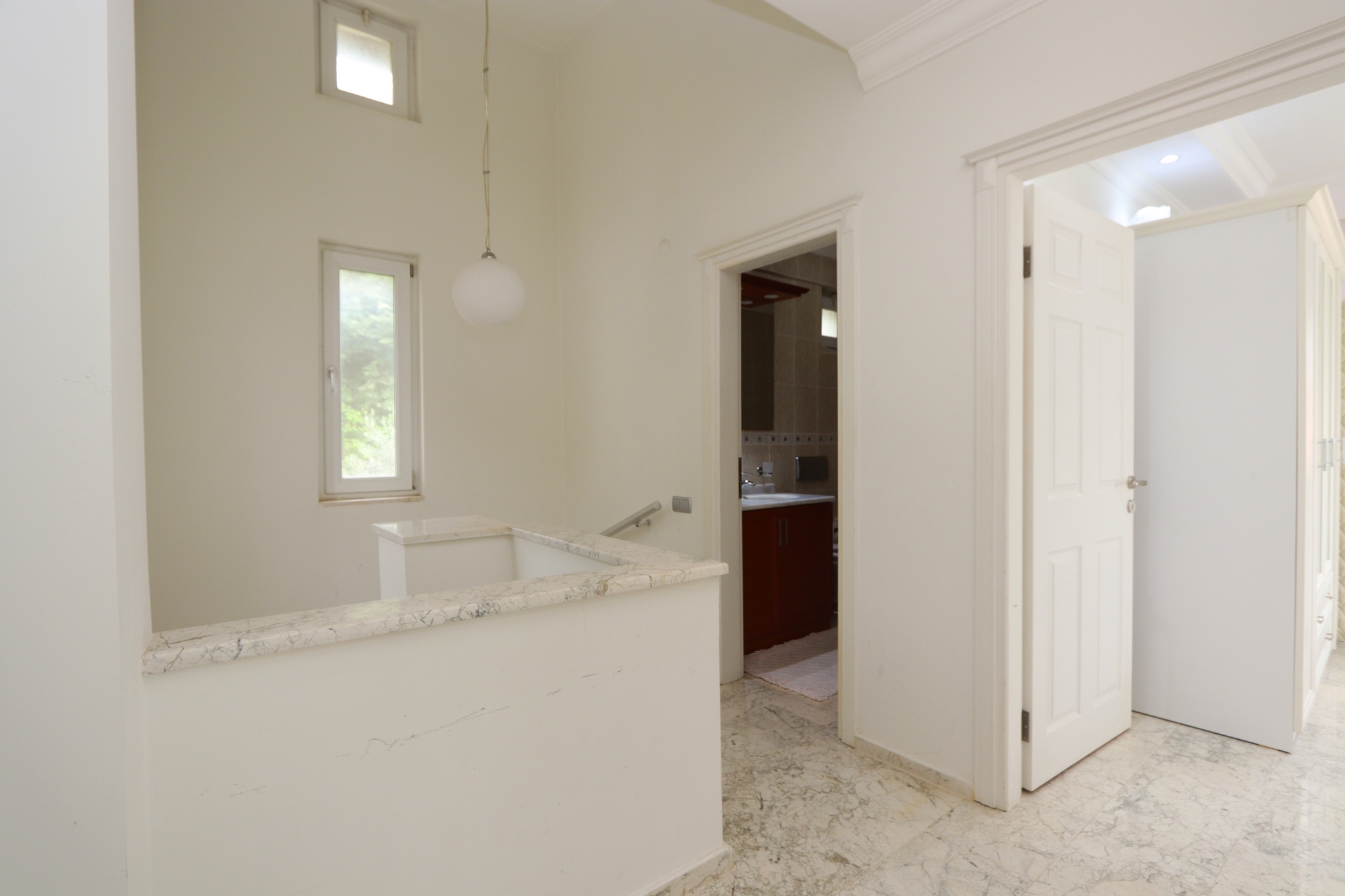 Kitchen with a light counter, marble worktop and two windows overlooking the garden in Alanya