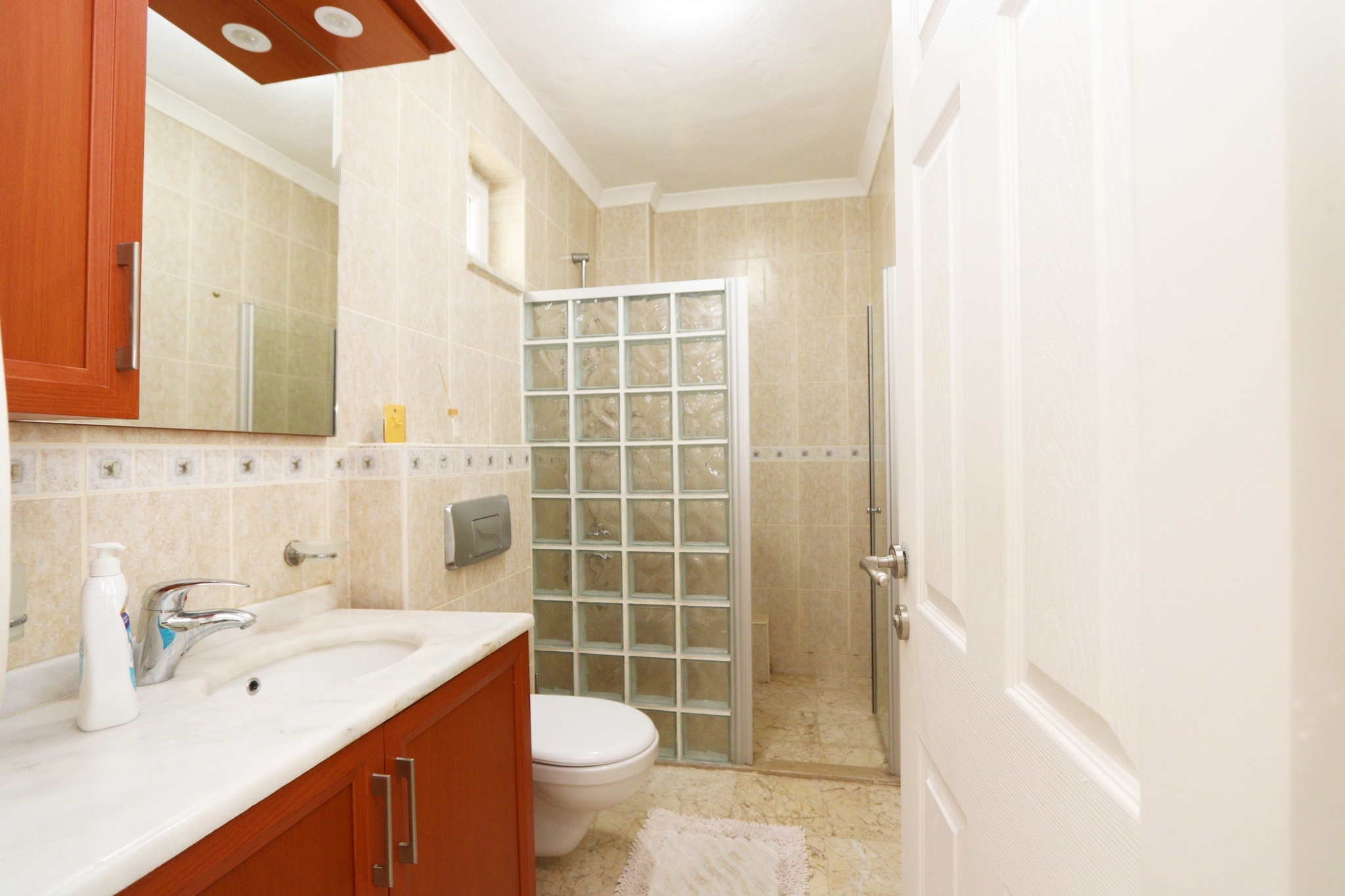 Bathroom with a glass-block shower, vanity and decorative tile border in Alanya