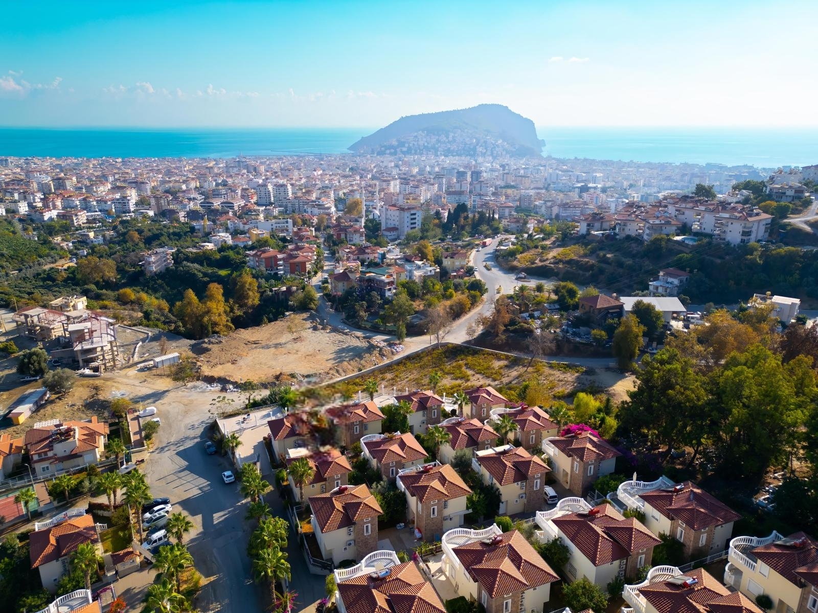 City panorama with a sea bay, mountain peninsula and red-tiled roofs beside a villa in Turkey