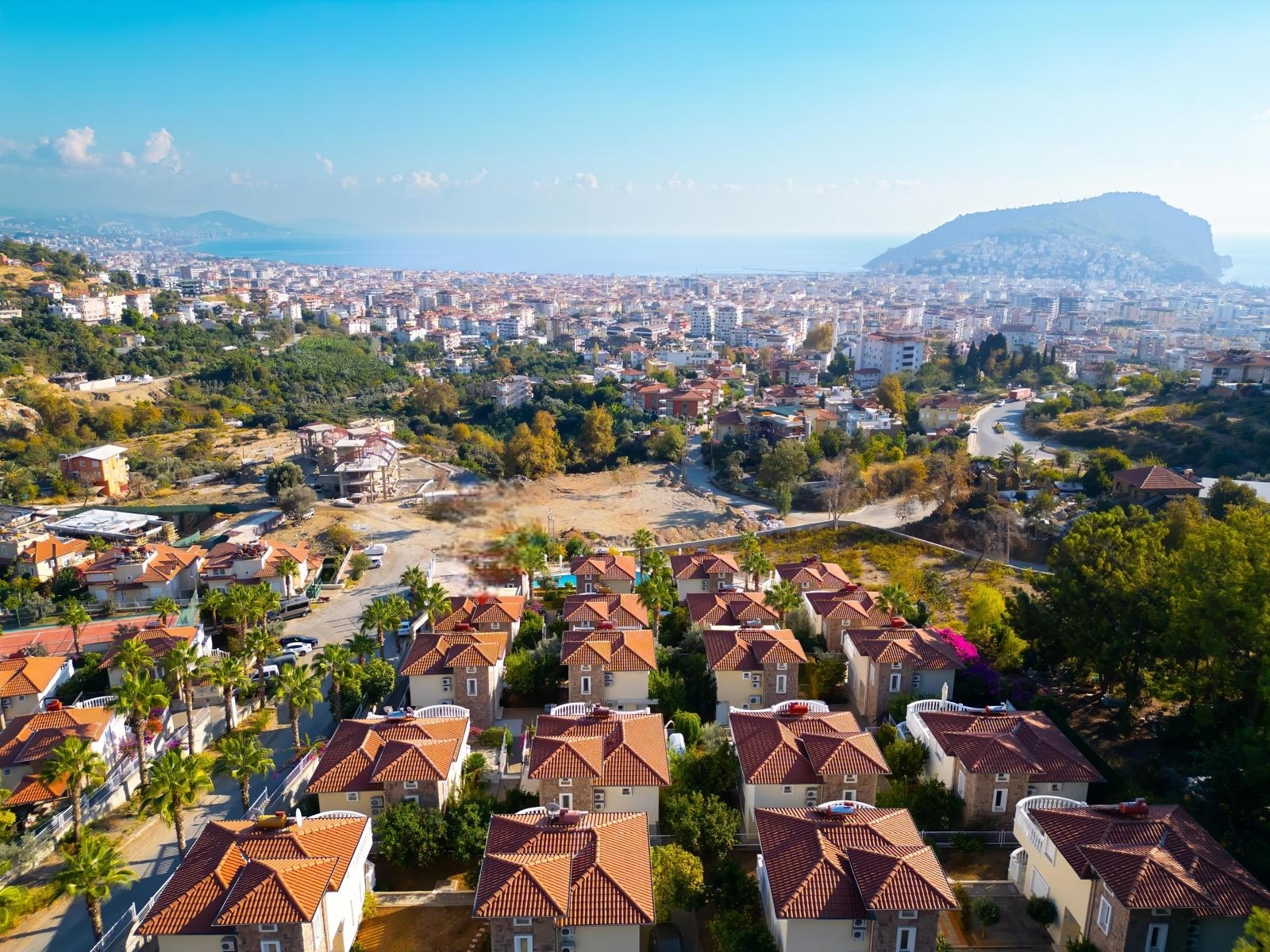 Panoramic view of the city, sea bay and green hills with a villa complex in Alanya
