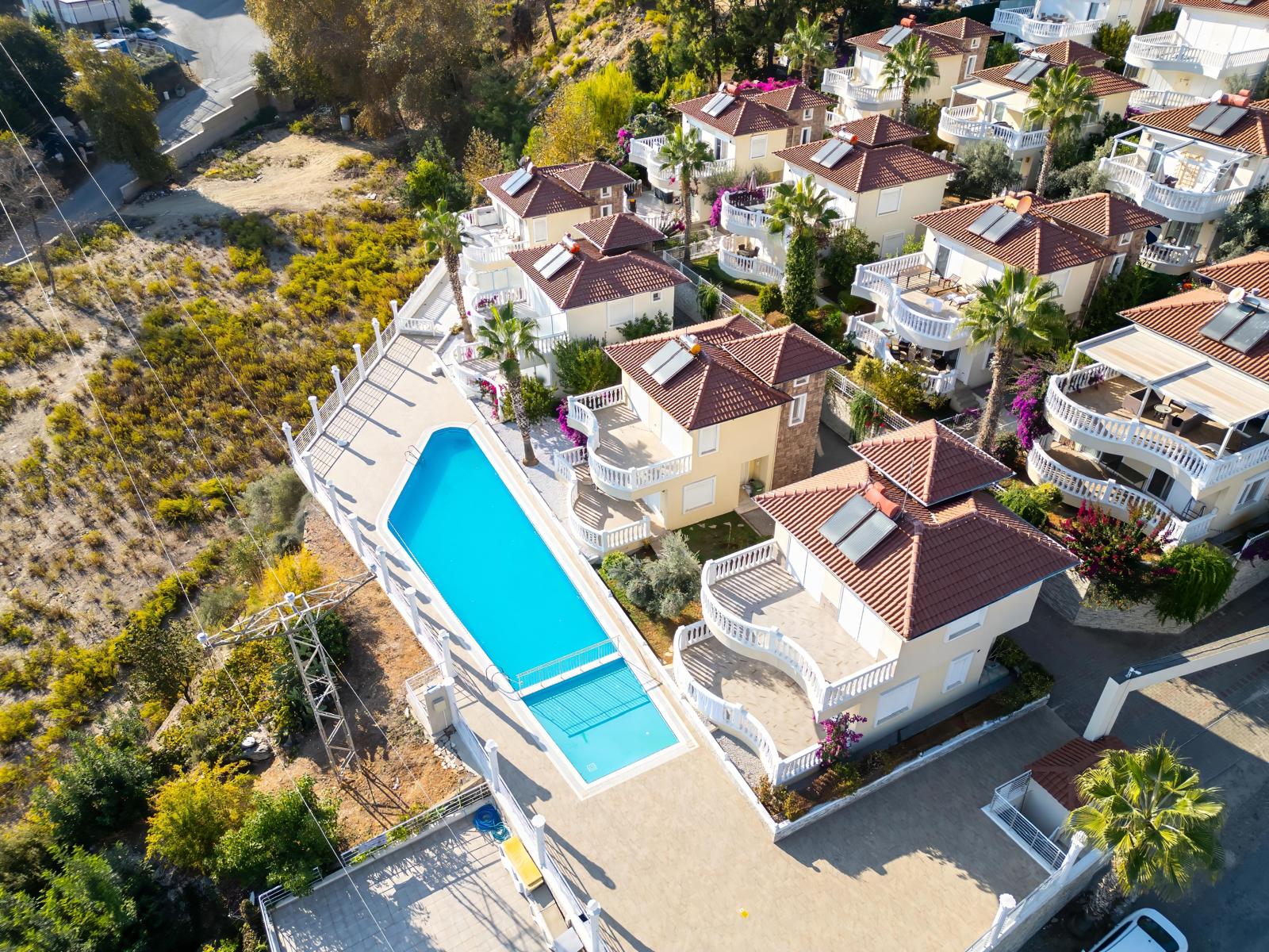 Rectangular outdoor pool with white villas and palms for residents of houses in Turkey