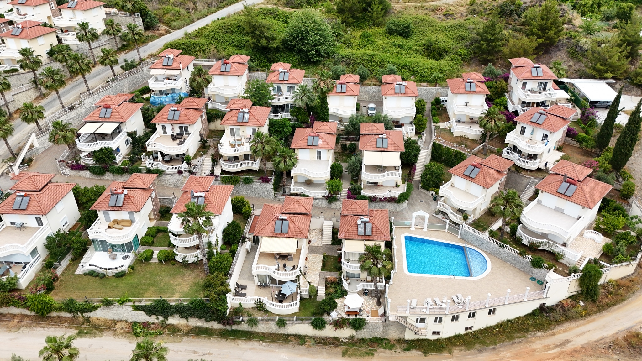 Low-rise villa complex with an oval pool and palms in Alanya where homes are for sale