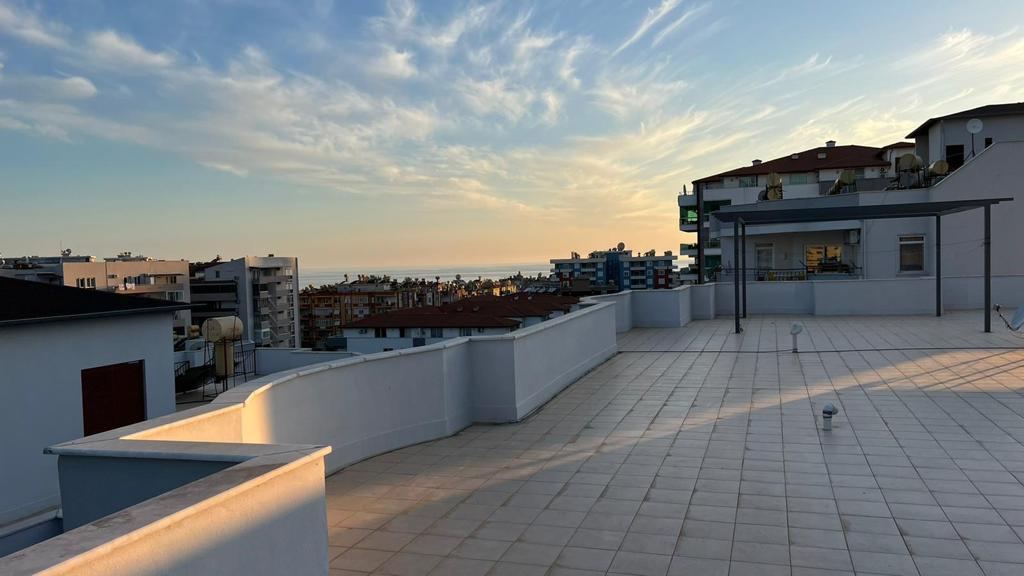 Evening rooftop terrace with sea views between residential buildings under cloudy skies