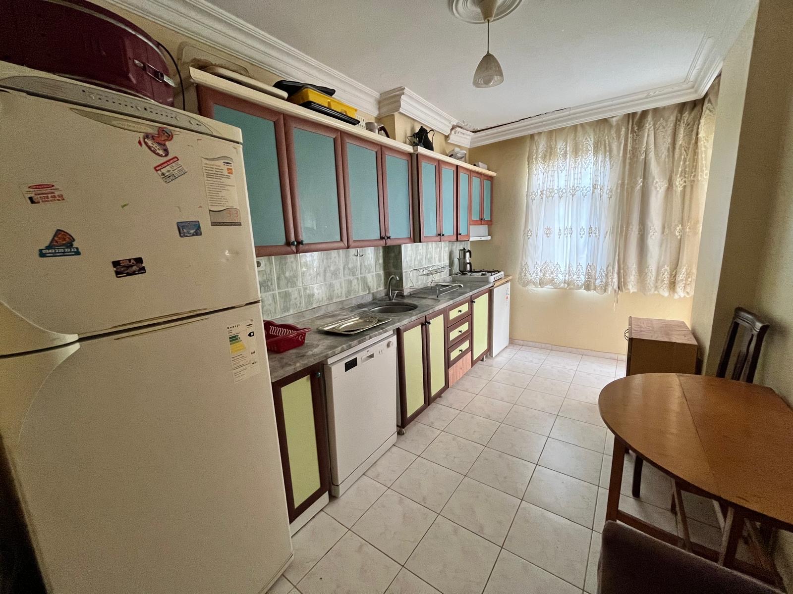 Kitchen with a linear cabinet set, gas stove, refrigerator and blue upper cupboards