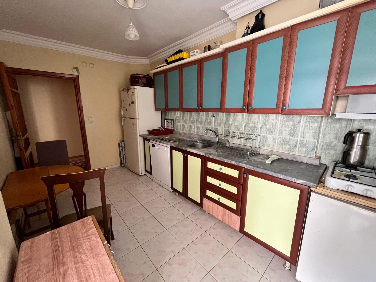 A kitchen with a gas stove and stone-look backsplash in a Tosmur apartment