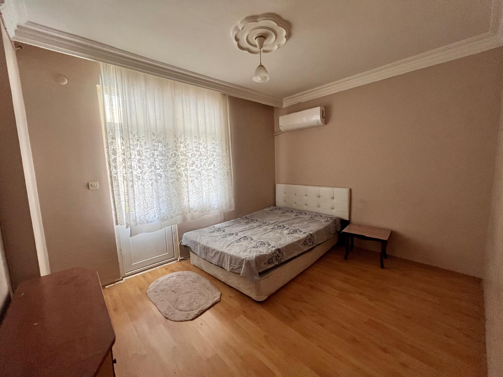 Bedroom with a double bed, upholstered headboard and balcony door in an apartment