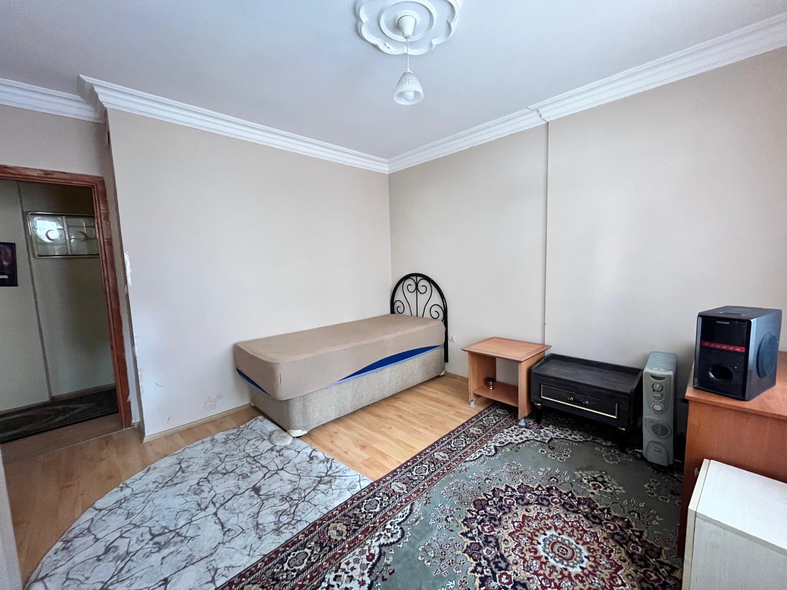 In the bedroom, a single bed, TV and wooden cabinet stand in a Tosmur apartment