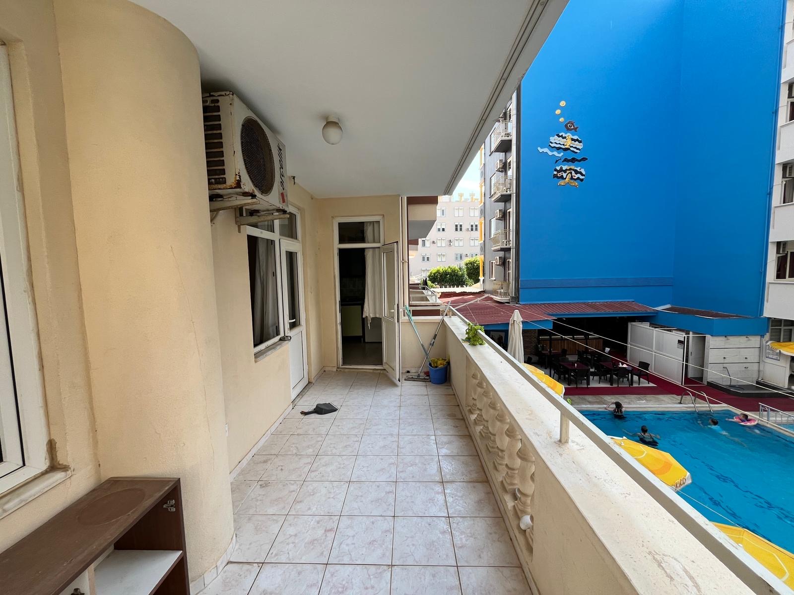 Covered balcony with a balustrade and potted plant overlooking the outdoor pool