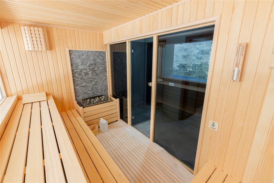Ahşap raflı sauna, taşlı sobası ve cam kapısıyla rezidans sakinlerinin kullanımına sunuluyor