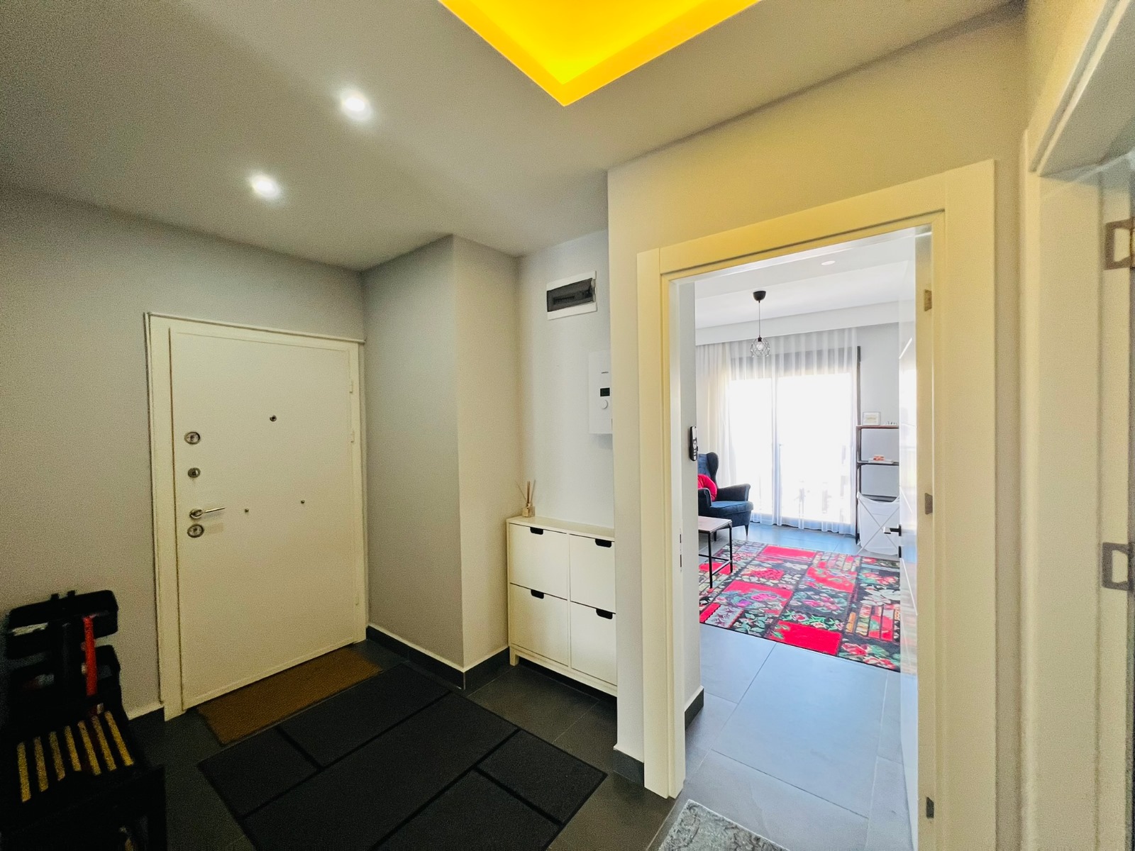Beyaz şifonyerli koridor, ayna kapısı ve yaşam alanına açılan kapısıyla penthouse içinde