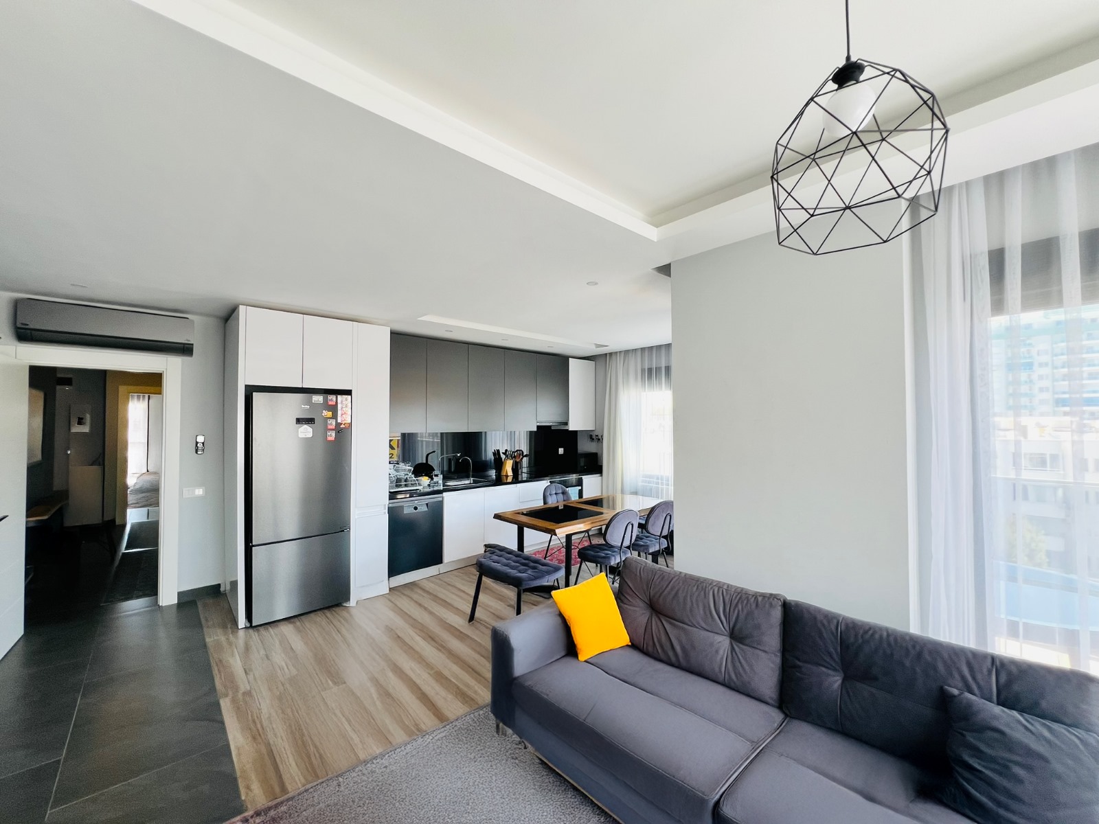 Beyaz gri mutfak mobilyalı mutfak-salon, panoramik penceresiyle penthouse içinde yer alıyor