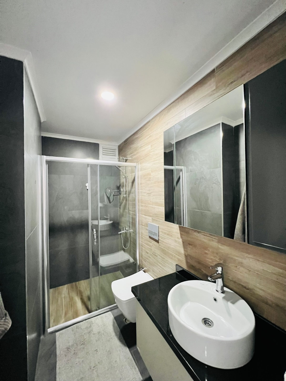 Beyaz lavabolu banyo, cam duş kabini ve geniş aynasıyla penthouse içinde yer alıyor