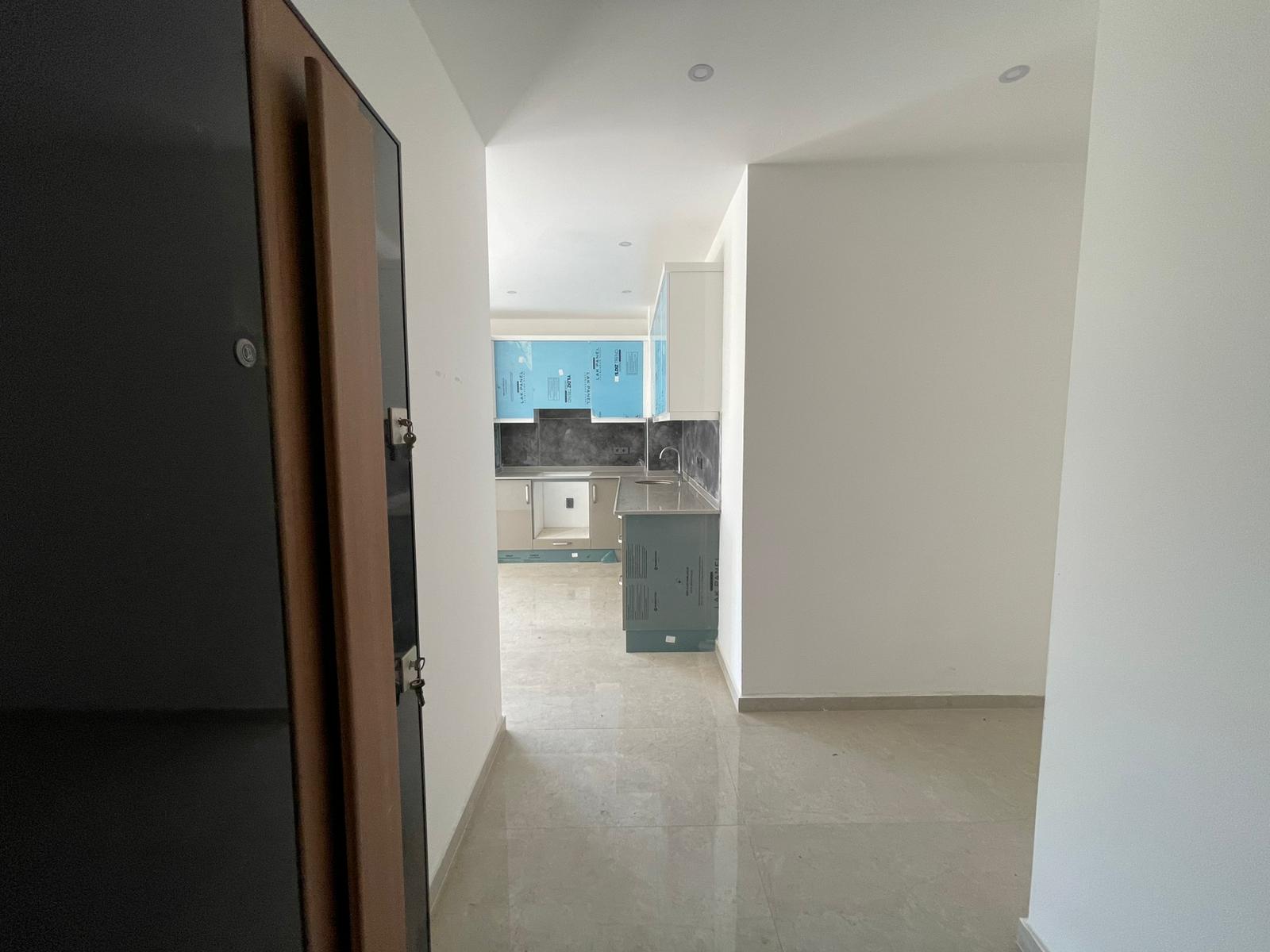 Parlak taş zeminli mutfak-salon, Oba'da 2+1 dairede koruyucu kaplamalı beyaz dolaplarla