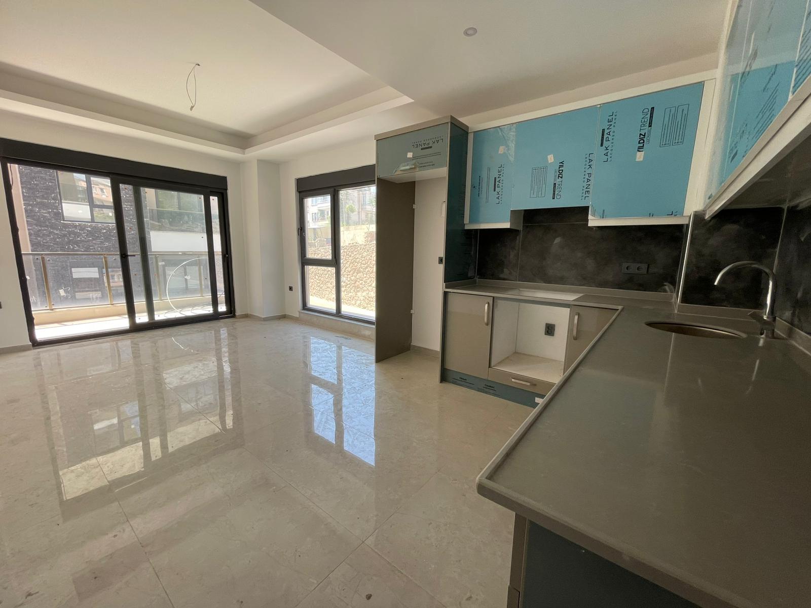 Koyu tezgâhlı köşe mutfak ve metal evye, Oba'da panoramik pencere yanında