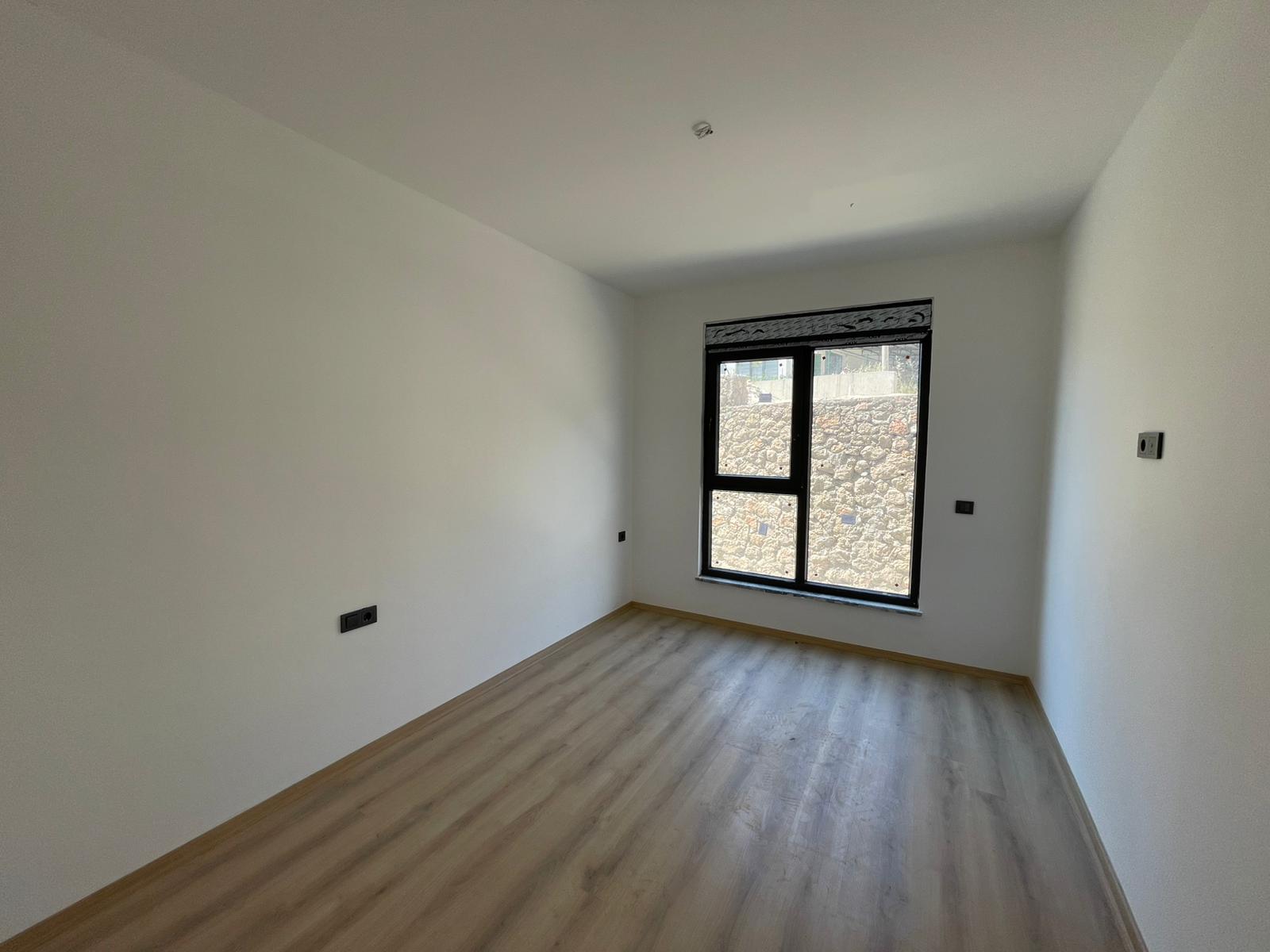 Siyah çerçeveli panoramik pencereli boş dikdörtgen oda, ahşap görünümlü laminant ve spot ışıkla