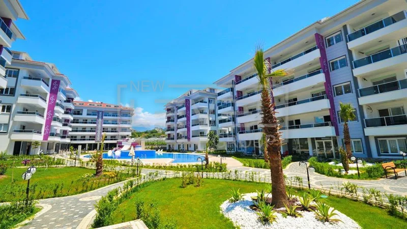 Açık havuz ve palmiyeler arasındaki site: Kestel’de Alanya’da Türkiye’de satılık 2+1 daire — New Level Group