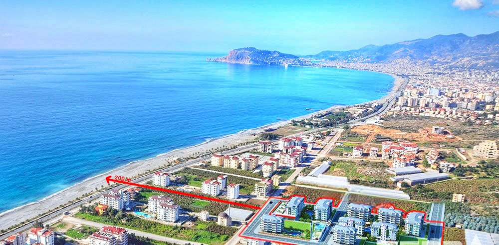 Panoramik kıyı şeridi ve mavi deniz Türkiye’de satılık dairelerin bulunduğu kompleksi gösteriyor