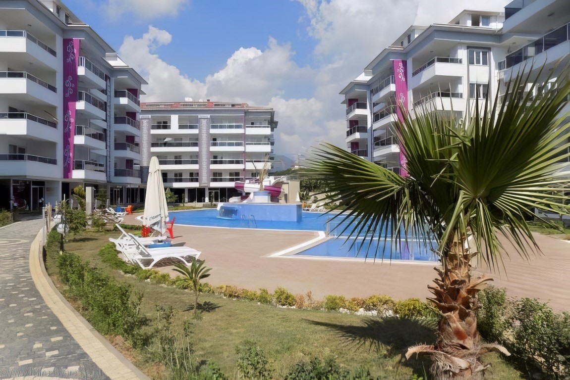 Sığ bölümlü açık havuz Kestel’de satışta olan konutların arasındaki palmiyeli alanda