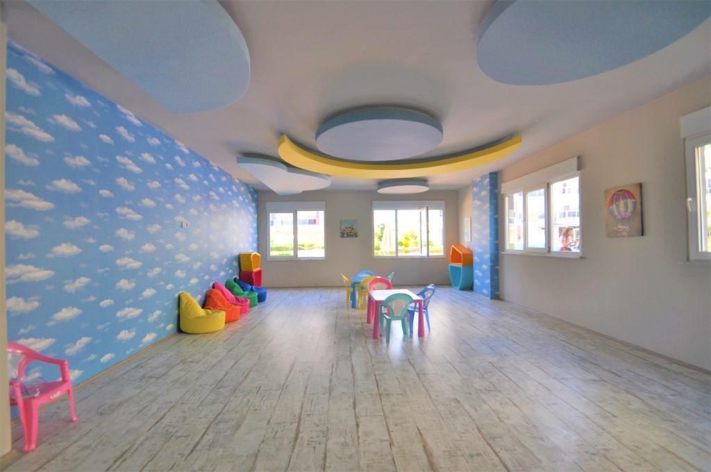 Çocuk oyun alanı renkli puflar ve bahçeye bakan panoramik pencerelerle düzenlenmiş