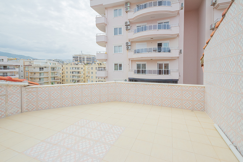 Açık teras geometrik korkuluklarıyla şehir ve dağ manzarasına bakan penthouse içinde