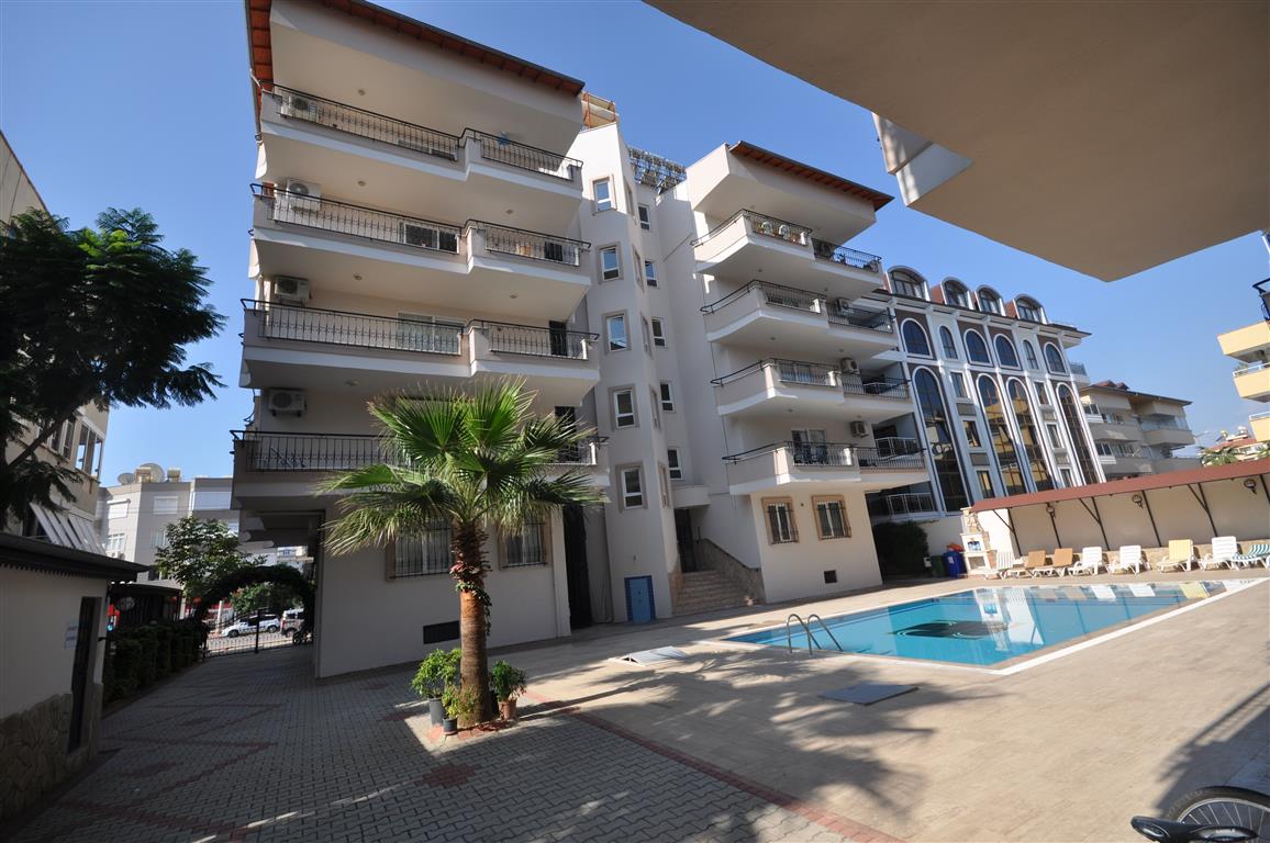 Şezlonglu açık havuz ve palmiye apartman dairelerinin bulunduğu komplekste Alanya’da