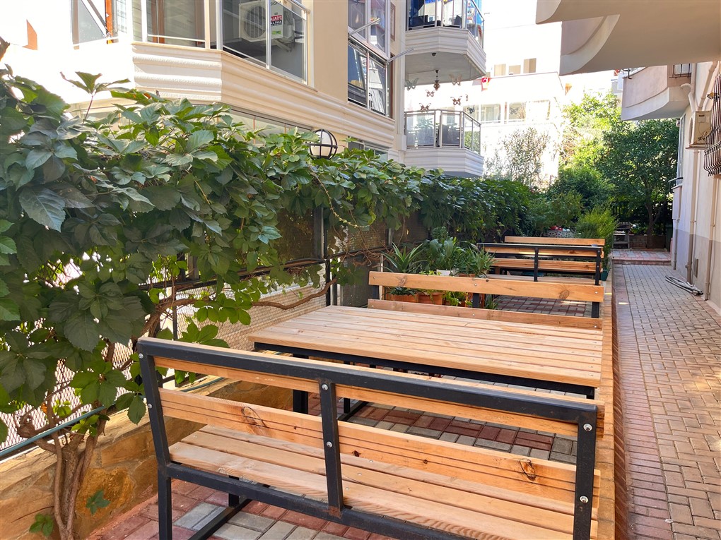 Ahşap masa ve banklarla düzenlenen taş döşeli alan penthouse sakinleri için