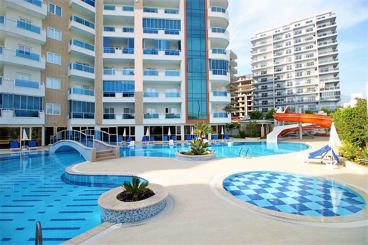 Outdoor pool with a water slide and arched bridge in an apartment complex in Mahmutlar, Turkey