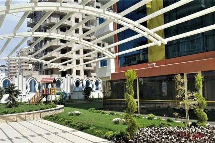 Landscaped grounds with a white pergola and playground in a complex with 1+1 apartments for sale in Turkey
