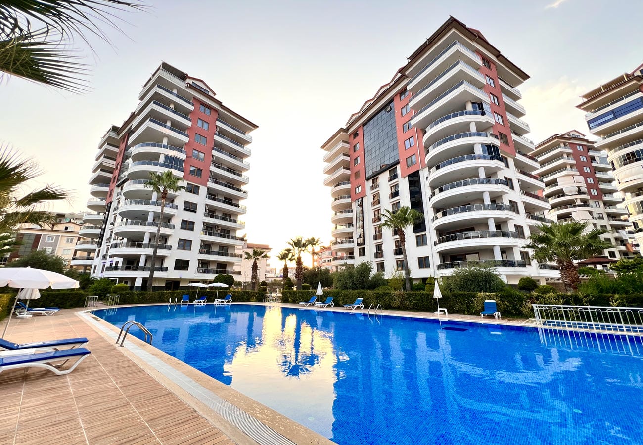Akşam ışığında şemsiyeli açık havuz Çikcilli’de Türkiye’deki 4+1 dairelerin bulunduğu sitede