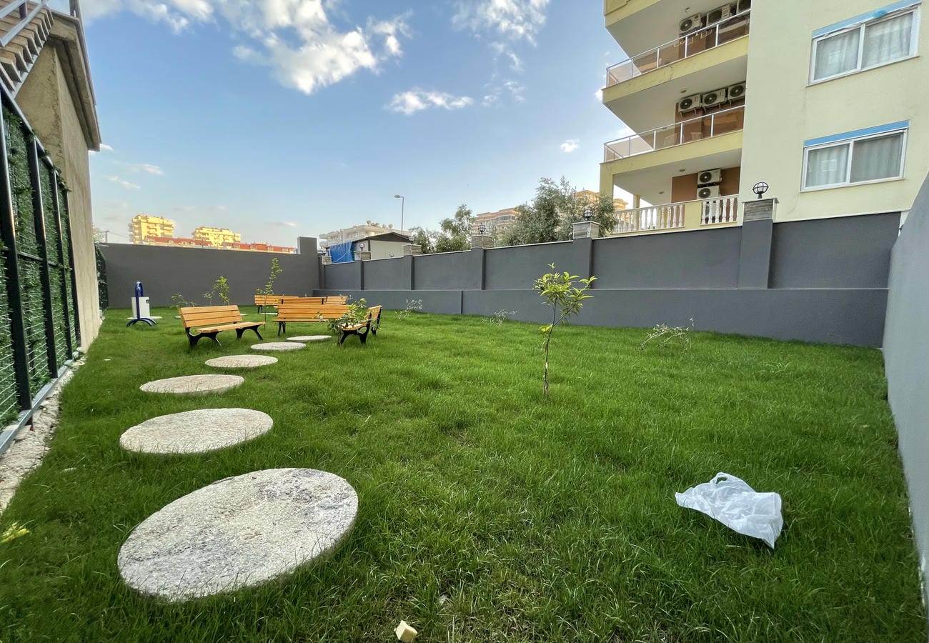 Green lawn with benches and an outdoor exercise machine for residents of apartments in Mahmutlar, Turkey