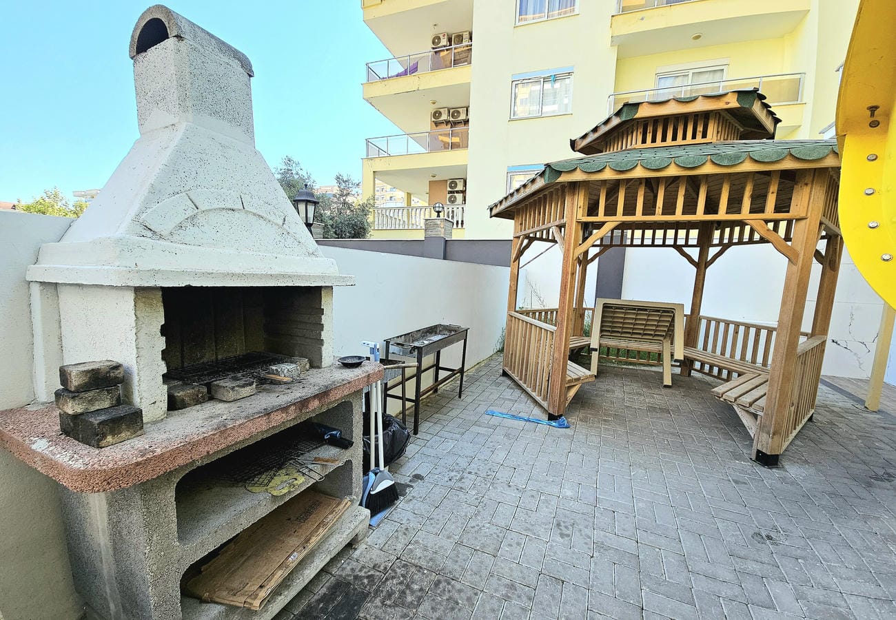 Covered gazebo with benches and an outdoor fireplace near apartment buildings for sale in Turkey