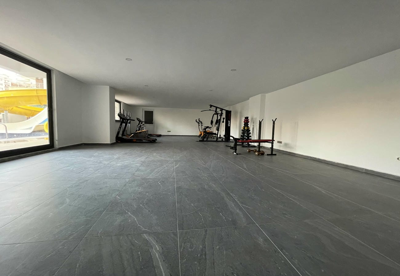 Gym with dumbbells and treadmills in a complex with apartments in Mahmutlar
